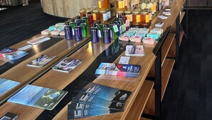 A reception area with a wooden counter displaying various products and brochures. - Hotel Motel Le Château (Lac-Megantic)