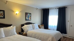 A hotel room with two beds, a nightstand with a phone, a wall-mounted lamp, and a window with dark curtains. - Hotel Motel Le Château (Lac-Megantic)