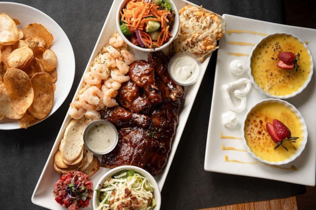 A variety of dishes including shrimp, ribs, chips, and a salad.
