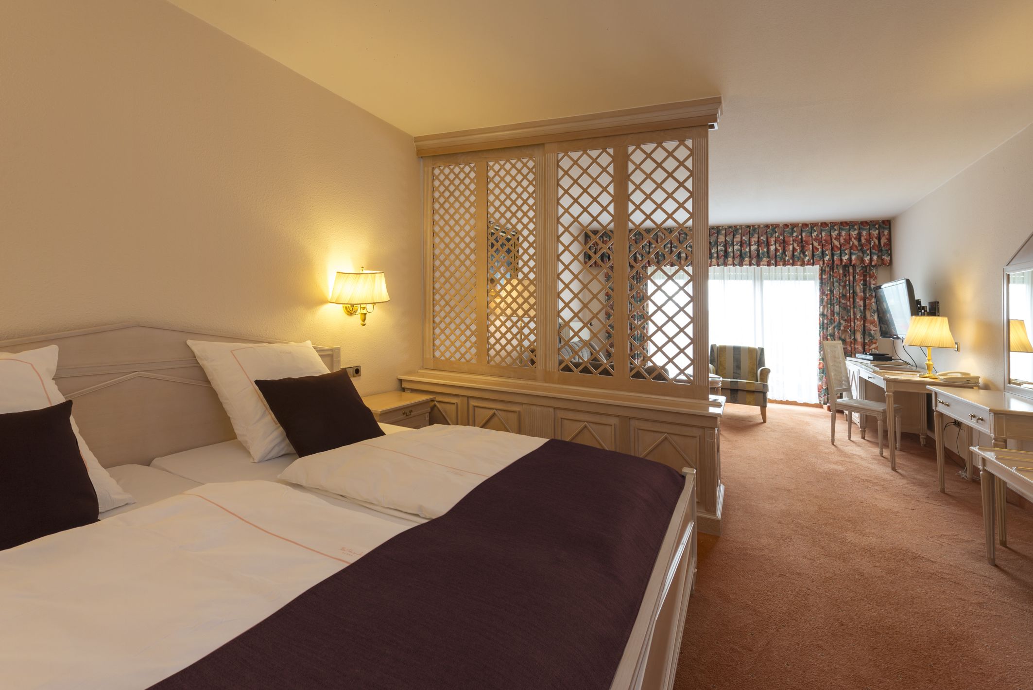 A hotel room with a bed, desk, and computer.