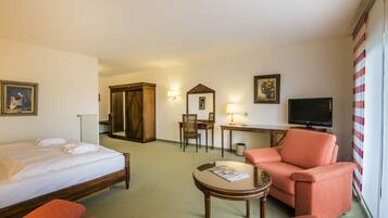 A hotel room with a bed, a desk, a television, and a sofa.