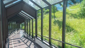 A covered walkway with glass panels and metal railings, leading to a lush green landscape. - Hôtel Eden au Lac (Echternach)