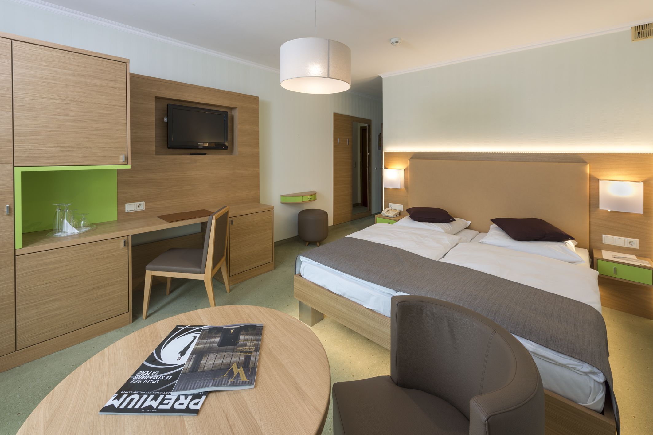 Et hotelværelse med seng, sengeborde, skrivebord, stol, fjernsyn og lampe.