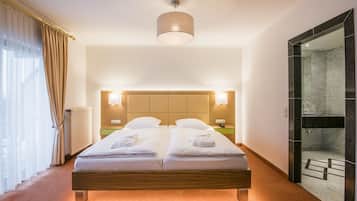 A double bed with a wooden headboard, two bedside tables with lamps, a large mirror, and a glass shower enclosure.