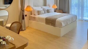 A modern hotel room with a large bed, bedside lamps, a flat-screen TV, a desk with a chair, and a large window with curtains.