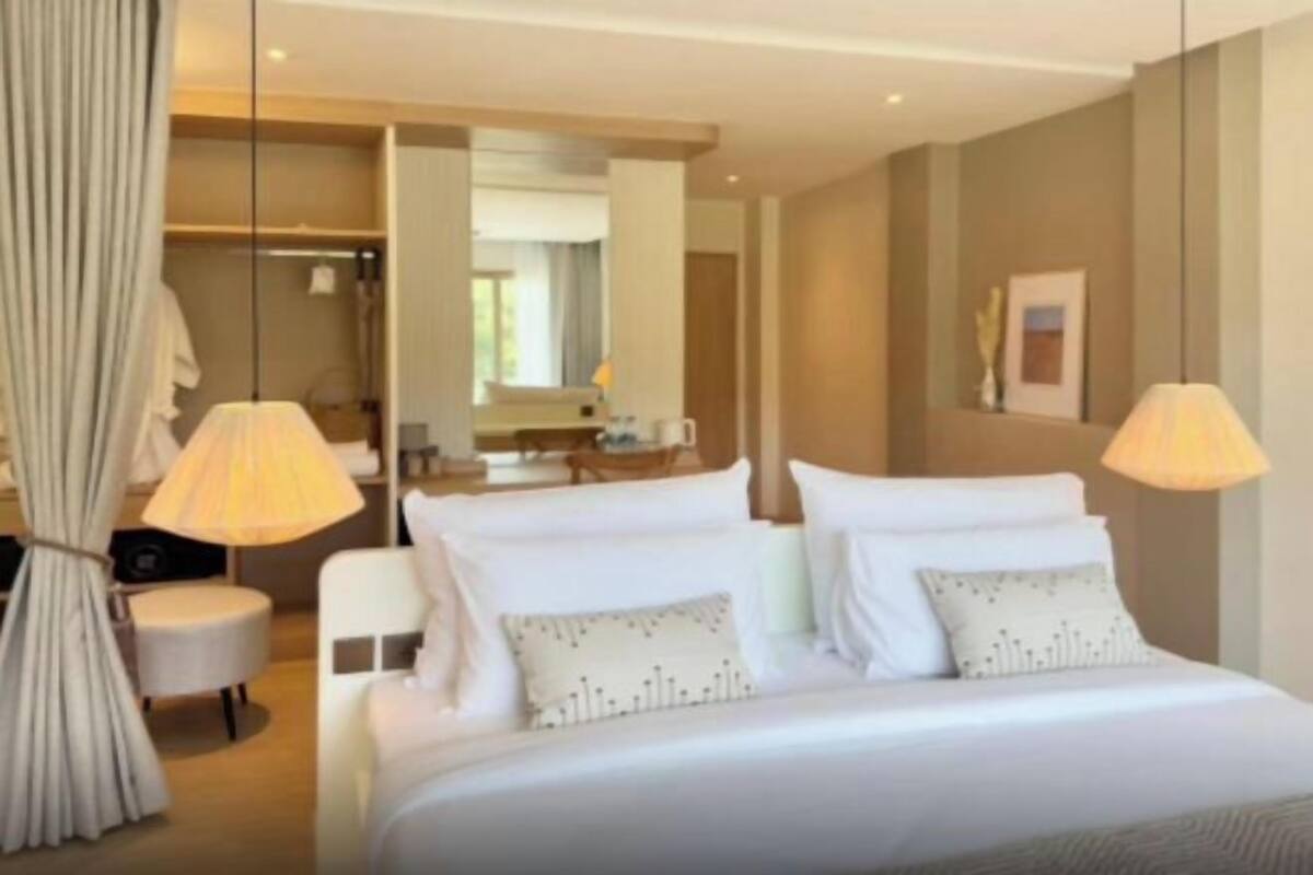 A hotel room with a bed, bedside lamps, a mirror, a wardrobe, and a chair.