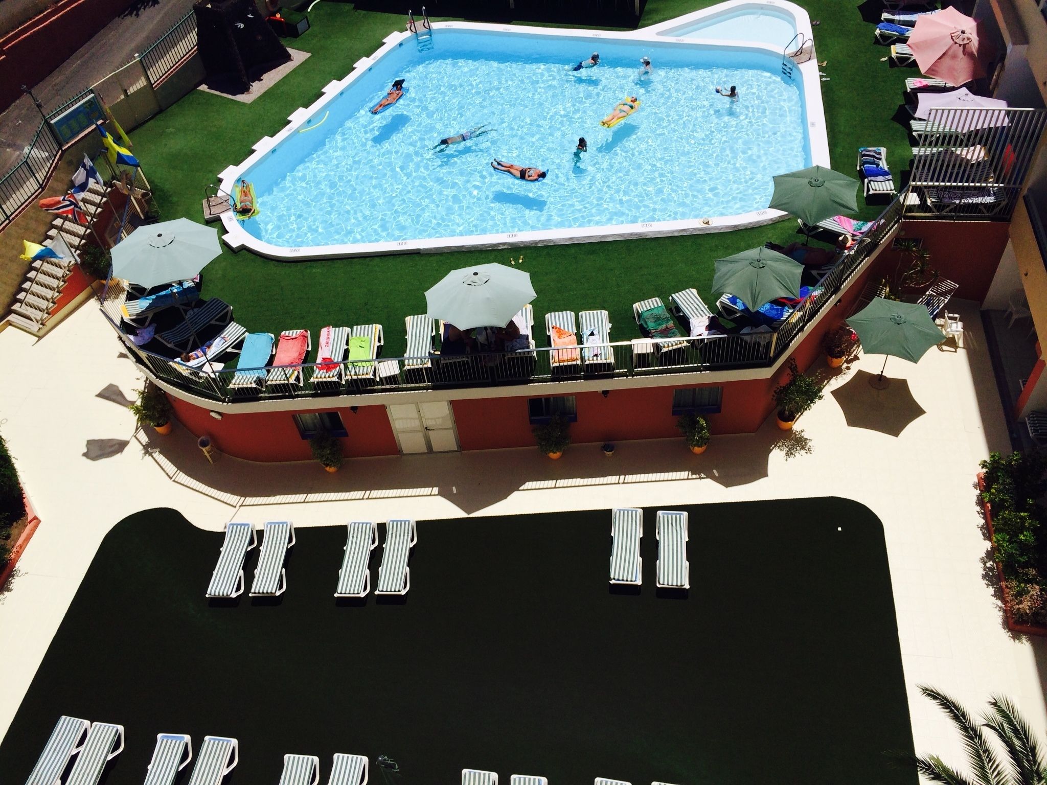 Ein Poolbereich auf dem Dach mit Liegestühlen und Sonnenschirmen.