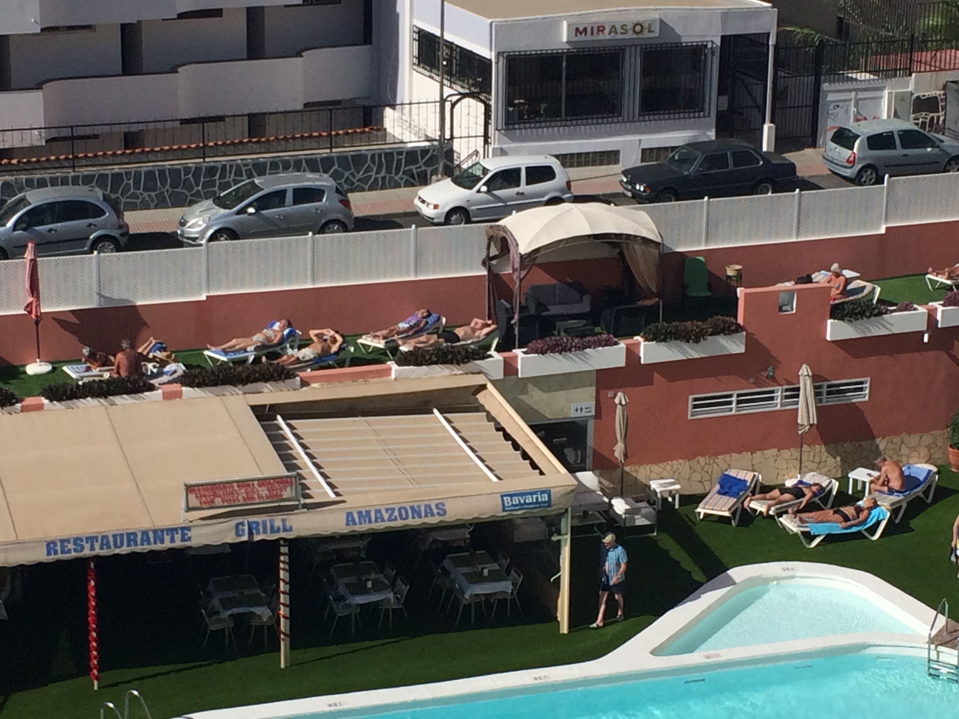 A rooftop bar with outdoor seating and a pool.