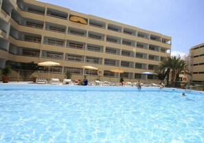 Un hotel con piscina, varios balcones y sombrillas.