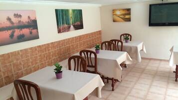 Un comedor con mesas y sillas, suelo de baldosas y obras de arte colgadas en la pared.