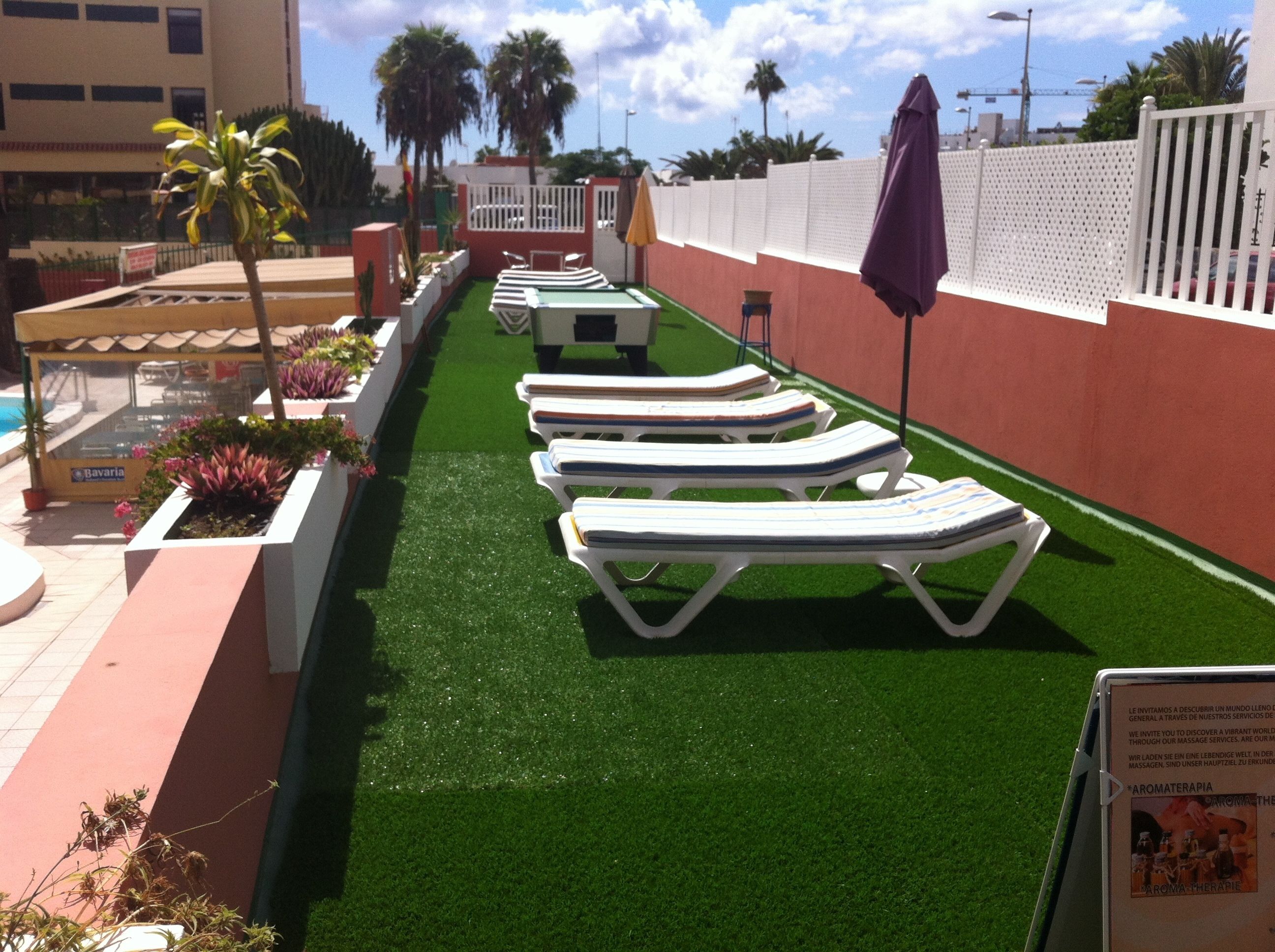 A poolside area with lounge chairs and artificial turf.