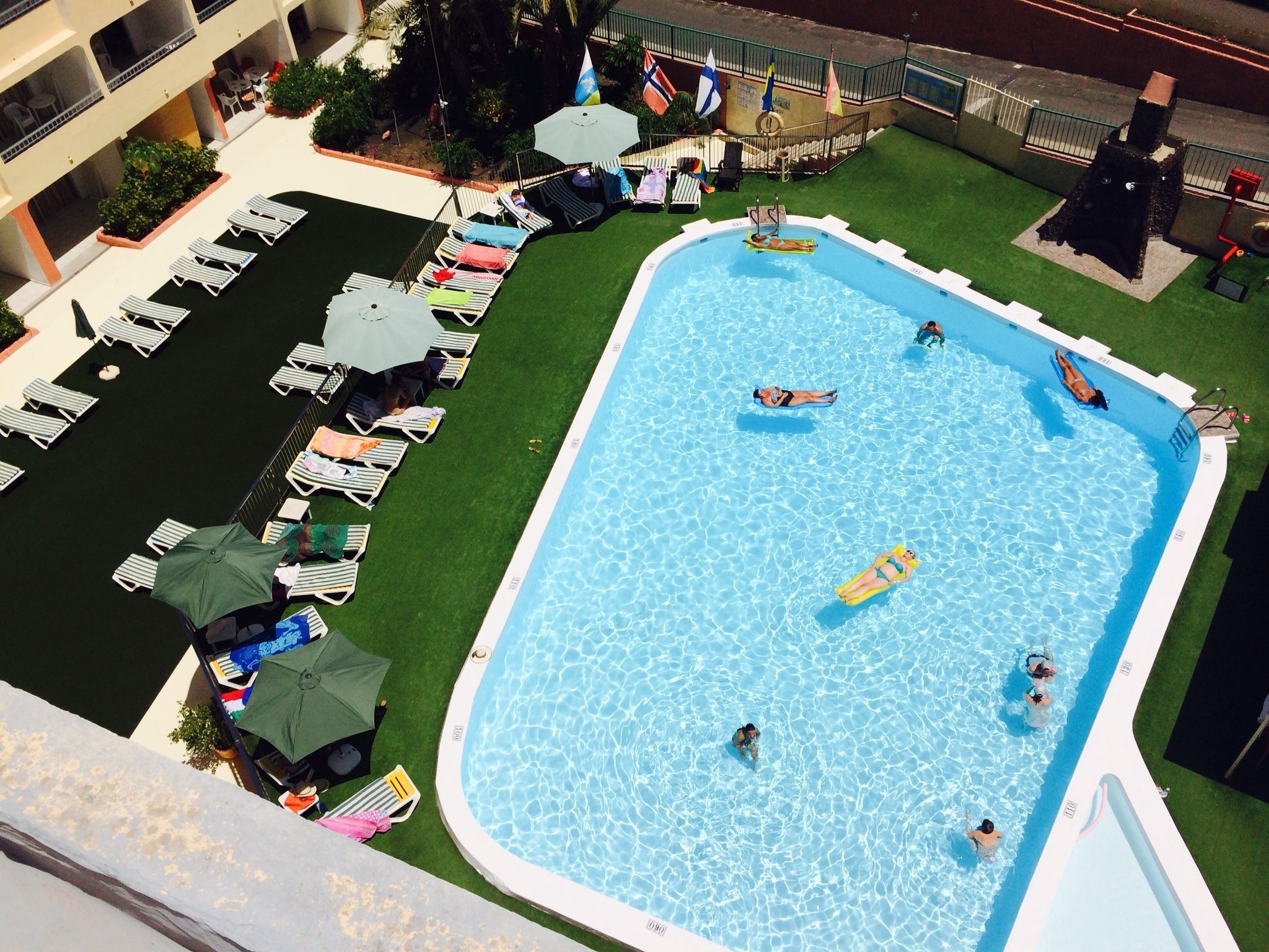 Piscina no terraço com várias espreguiçadeiras e guarda-sóis.