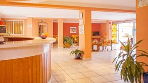 Eine Hotelhalle mit Empfangstresen, Sitzgelegenheiten und einem Fernseher.