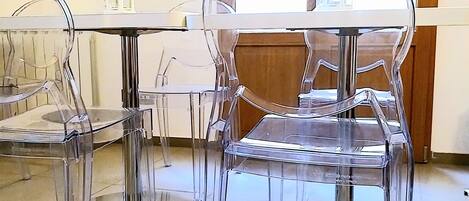 Una mesa y sillas de vidrio transparente en una habitación con suelo de baldosas y detalles de madera.