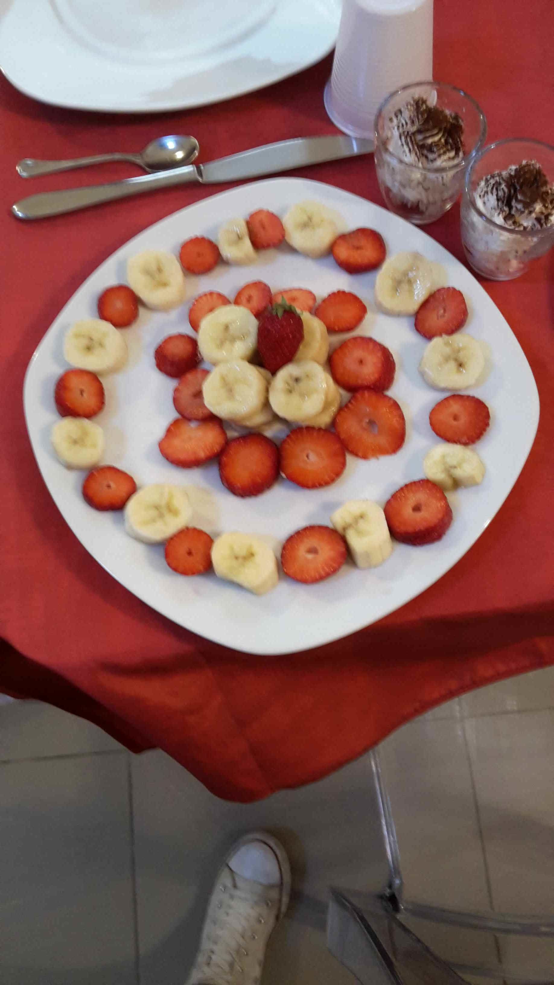 Un plato de rodajas de plátanos y fresas dispuestas en un círculo sobre un plato blanco.