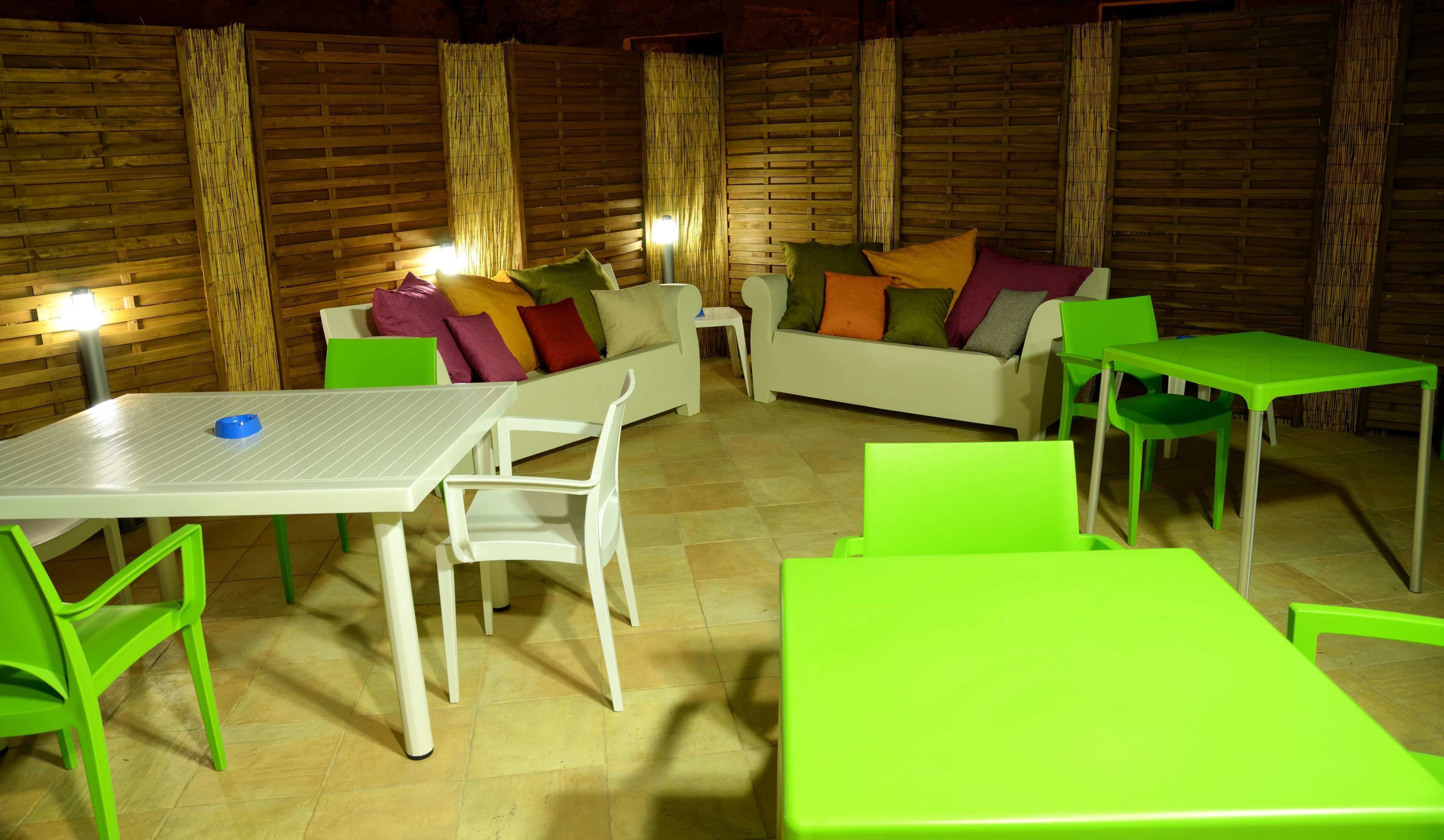 Una habitación acogedora con un sofá blanco, sillas verdes y una mesa blanca.
