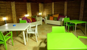 Una habitación acogedora con un sofá blanco, sillas verdes y una mesa blanca.