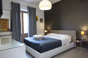 A modern hotel room with a large bed, a glass desk, and a bedside table with a lamp. - B&B Sogni d'oro (Agrigento)