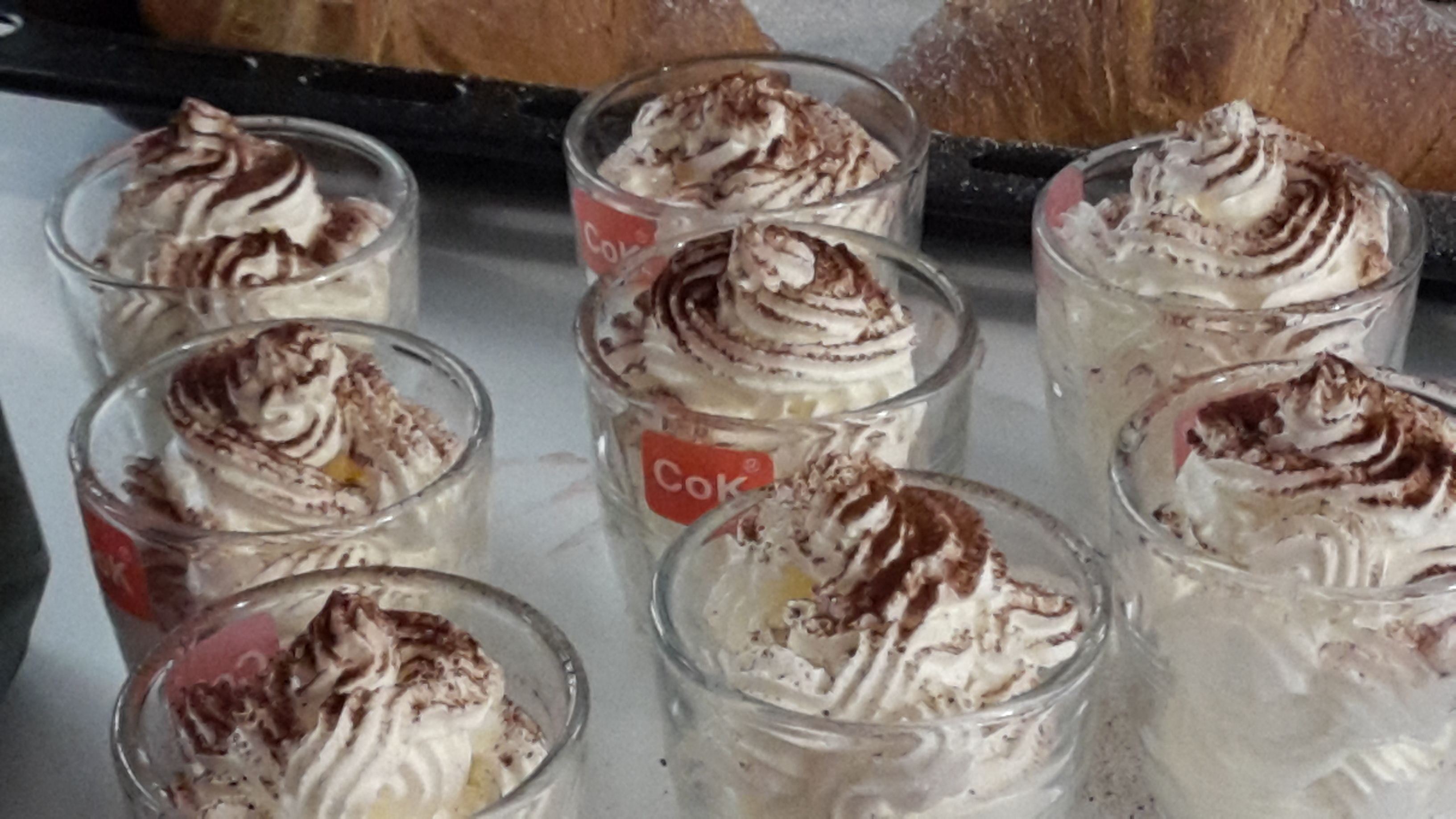 Una bandeja de copas de postre con crema batida y virutas de chocolate.