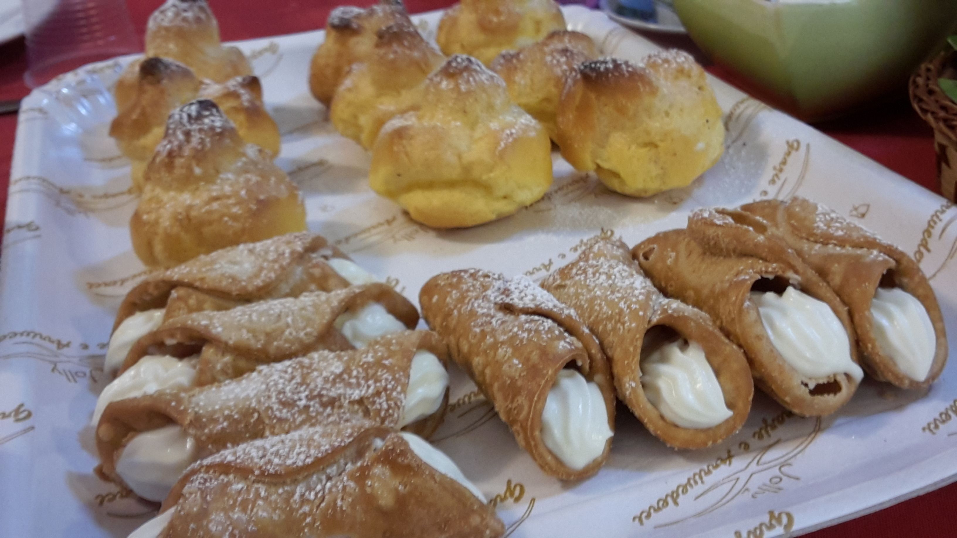 A plate of cream puffs and profiteroles on a table.