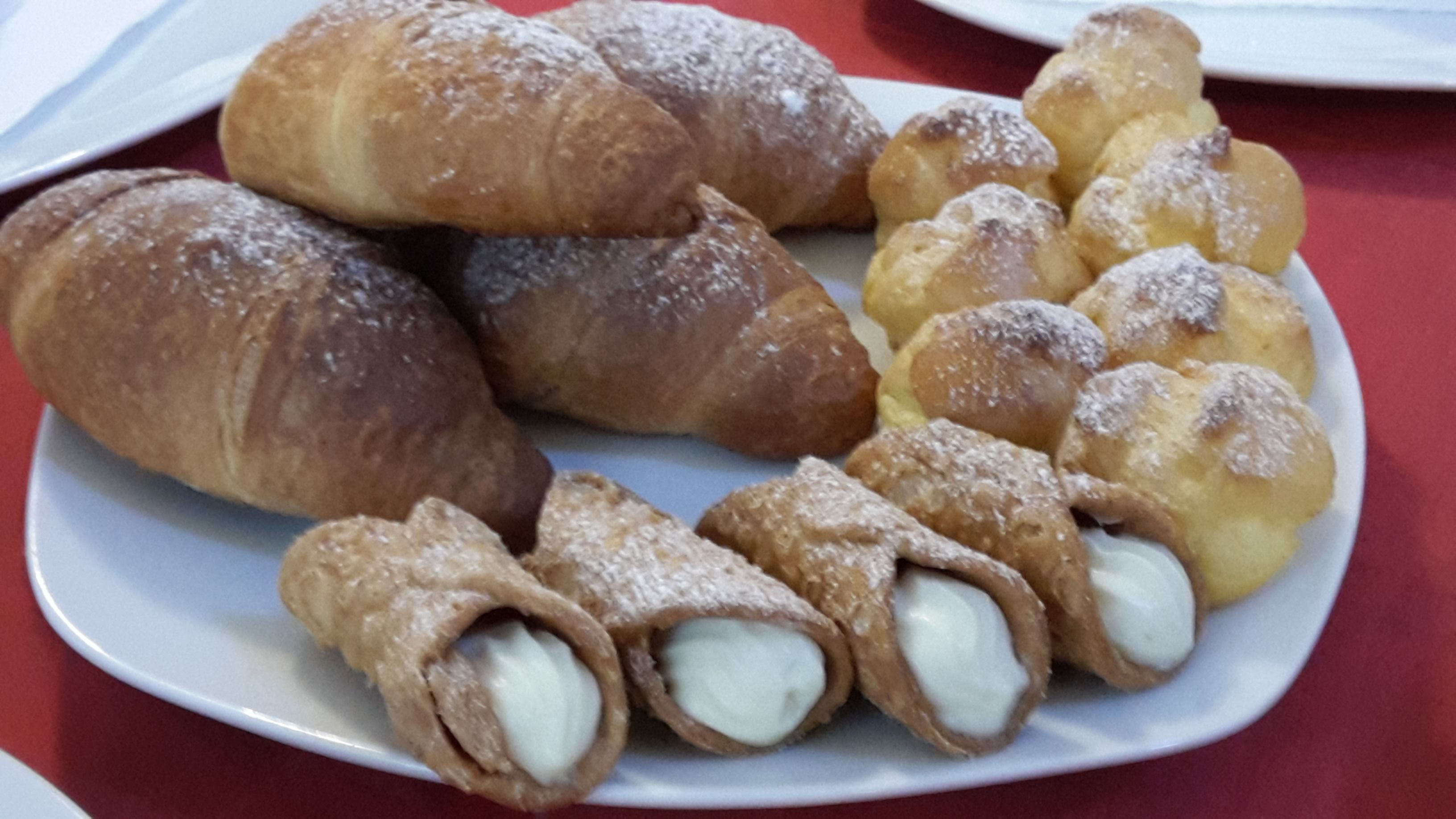 A plate of assorted pastries including croissants and cannoli.