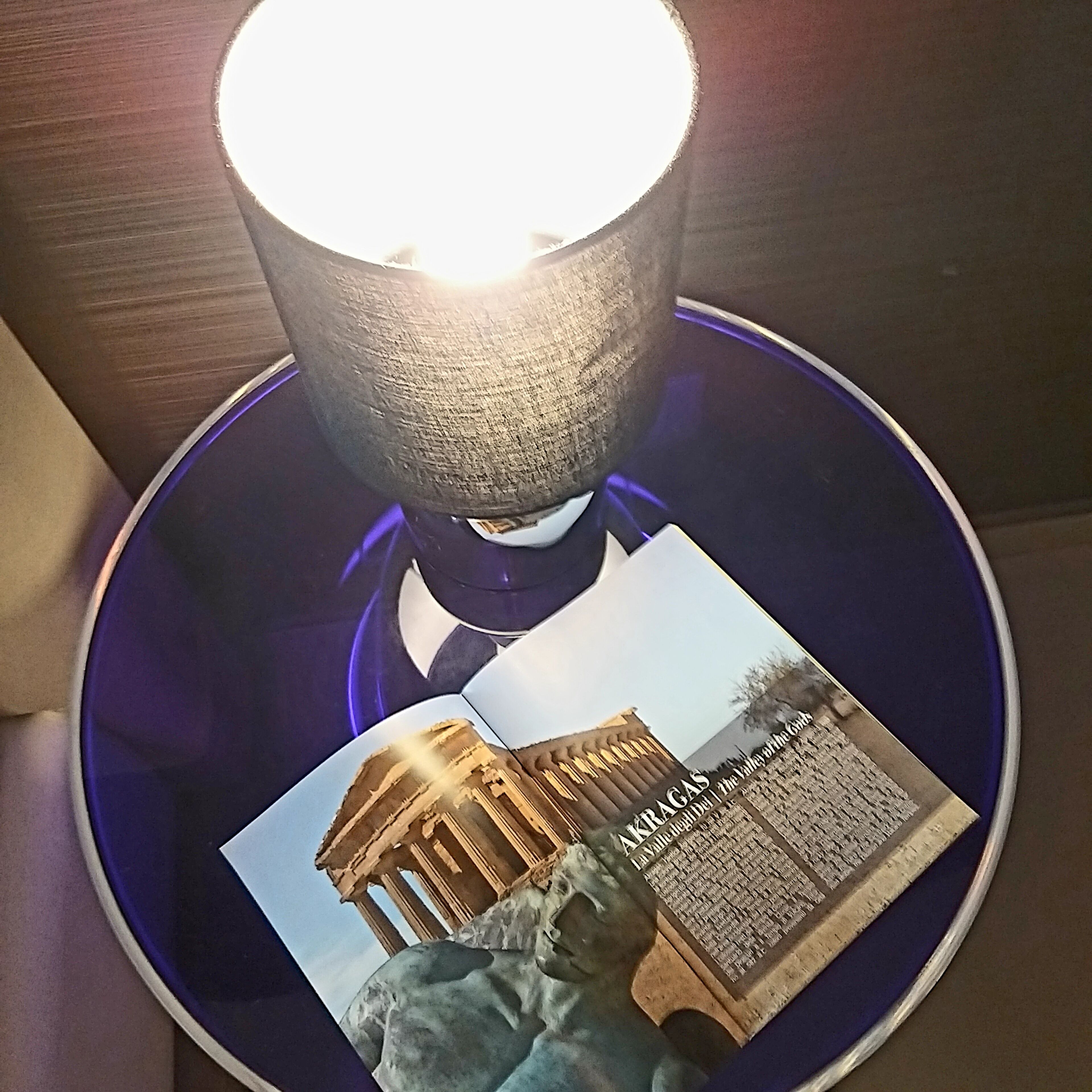 A table with a lamp, a brochure, and a statue.