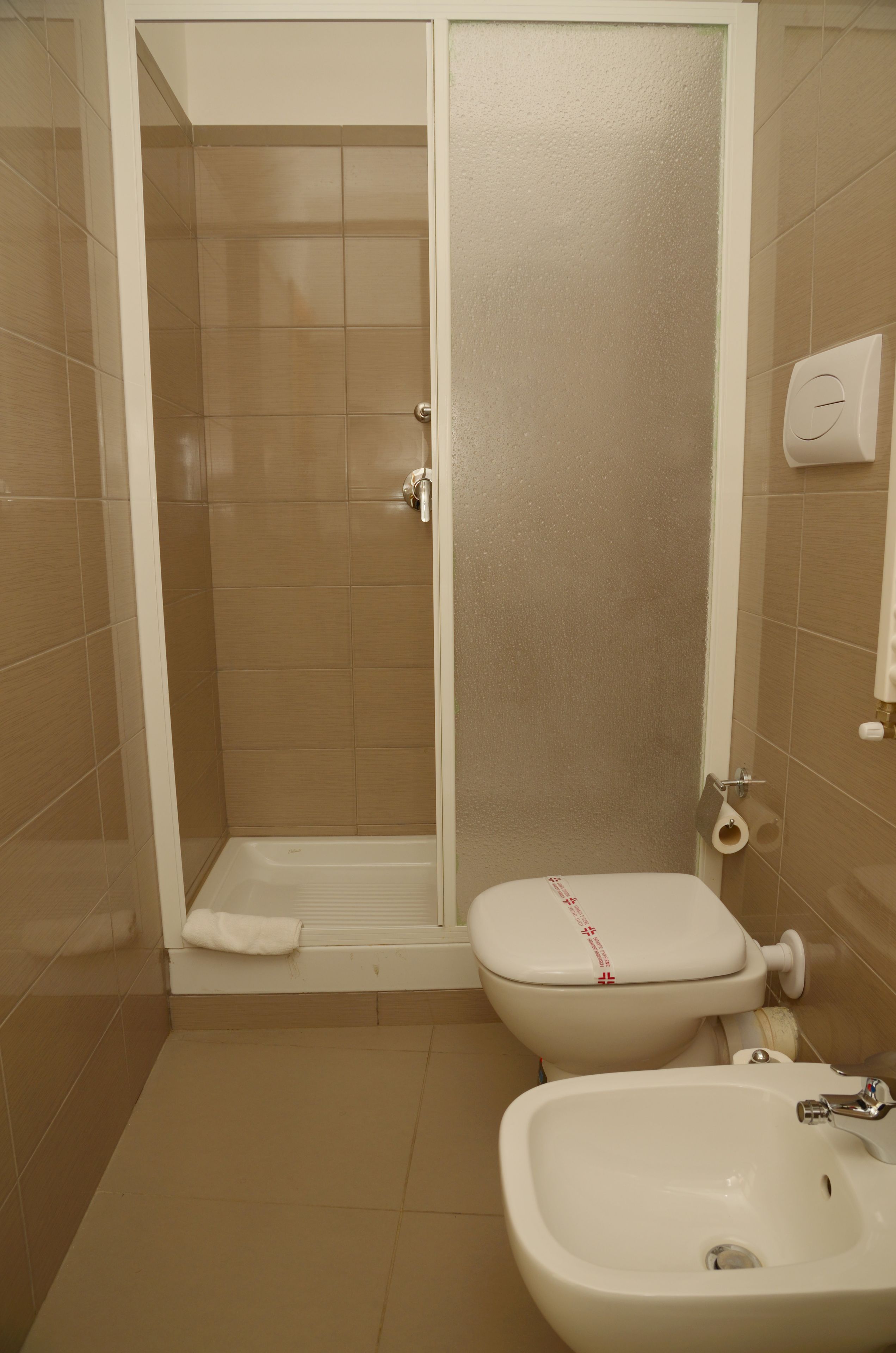 A bathroom with a shower enclosure, toilet, and sink.