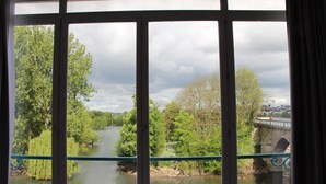 A view through a window with a view of a river, trees, and a bridge. - Hotel Restaurant L'Esturgeon (Poissy)