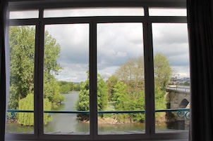 A view through a window with a view of a river, trees, and a bridge.
