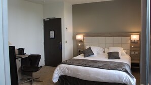 A hotel room with a bed, bedside lamps, a desk with a computer, and a chair. - Hotel Restaurant L'Esturgeon (Poissy)