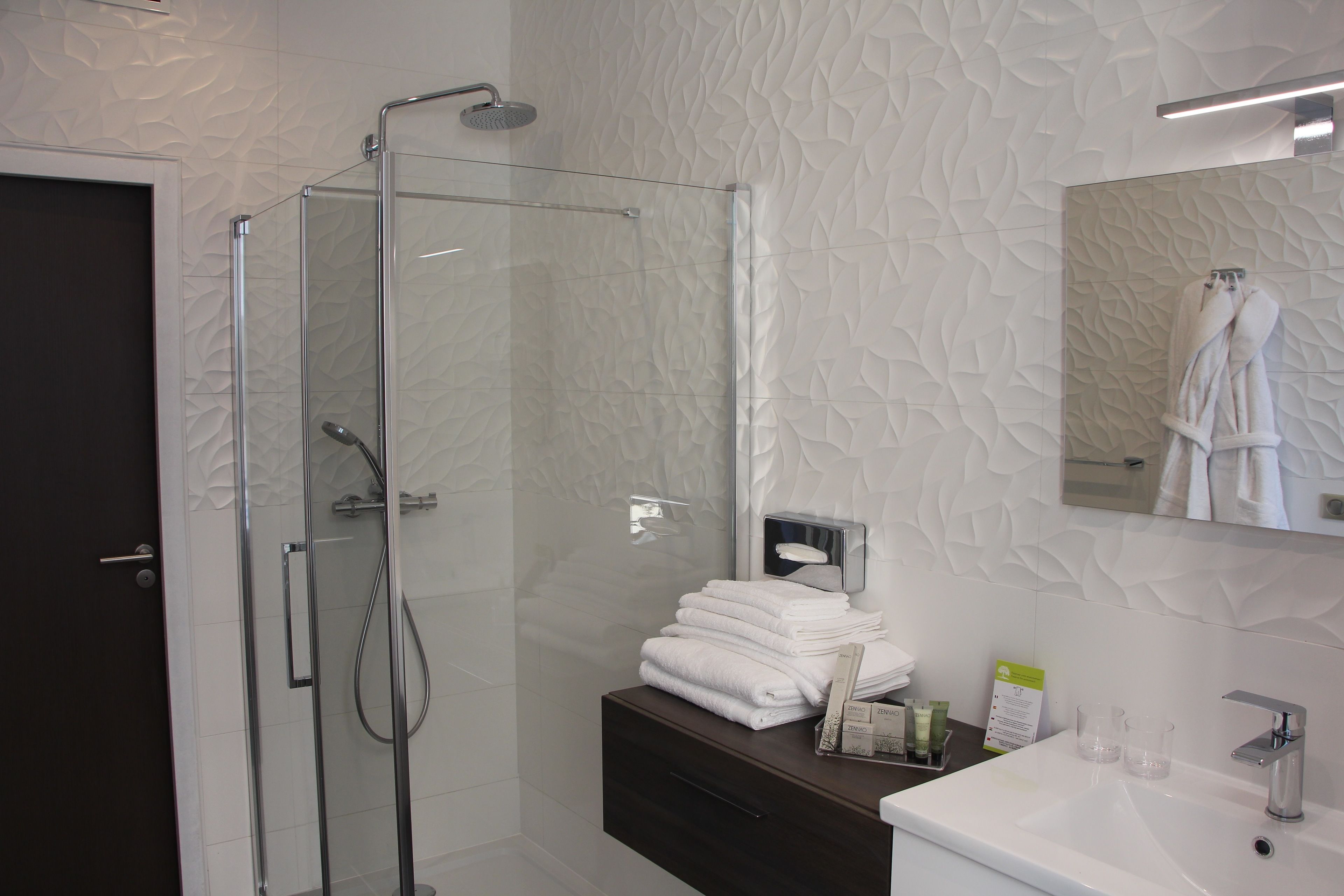 Un baño moderno con cabina de ducha de vidrio, tocador de madera oscura y lavabo blanco.