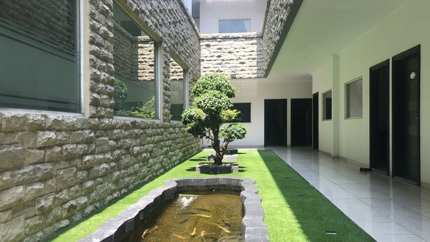 A modern building with stone walls, a koi pond, and a well-maintained lawn. - Hotel Sinar 3 (Sidoarjo)