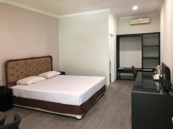 Habitación de hotel con cama, escritorio con computadora y armario.