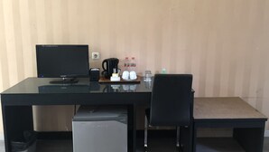 A modern office desk with a computer, coffee maker, and personal items. - Hotel Sinar 3 (Sidoarjo)