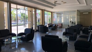 A spacious lobby with modern furniture, large windows, and a ceiling fan. - Hotel Sinar 3 (Sidoarjo)