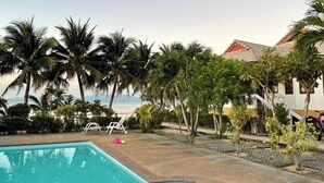 A swimming pool with palm trees and a view of the ocean. - Krisada Beach Resort (Koh Samui)