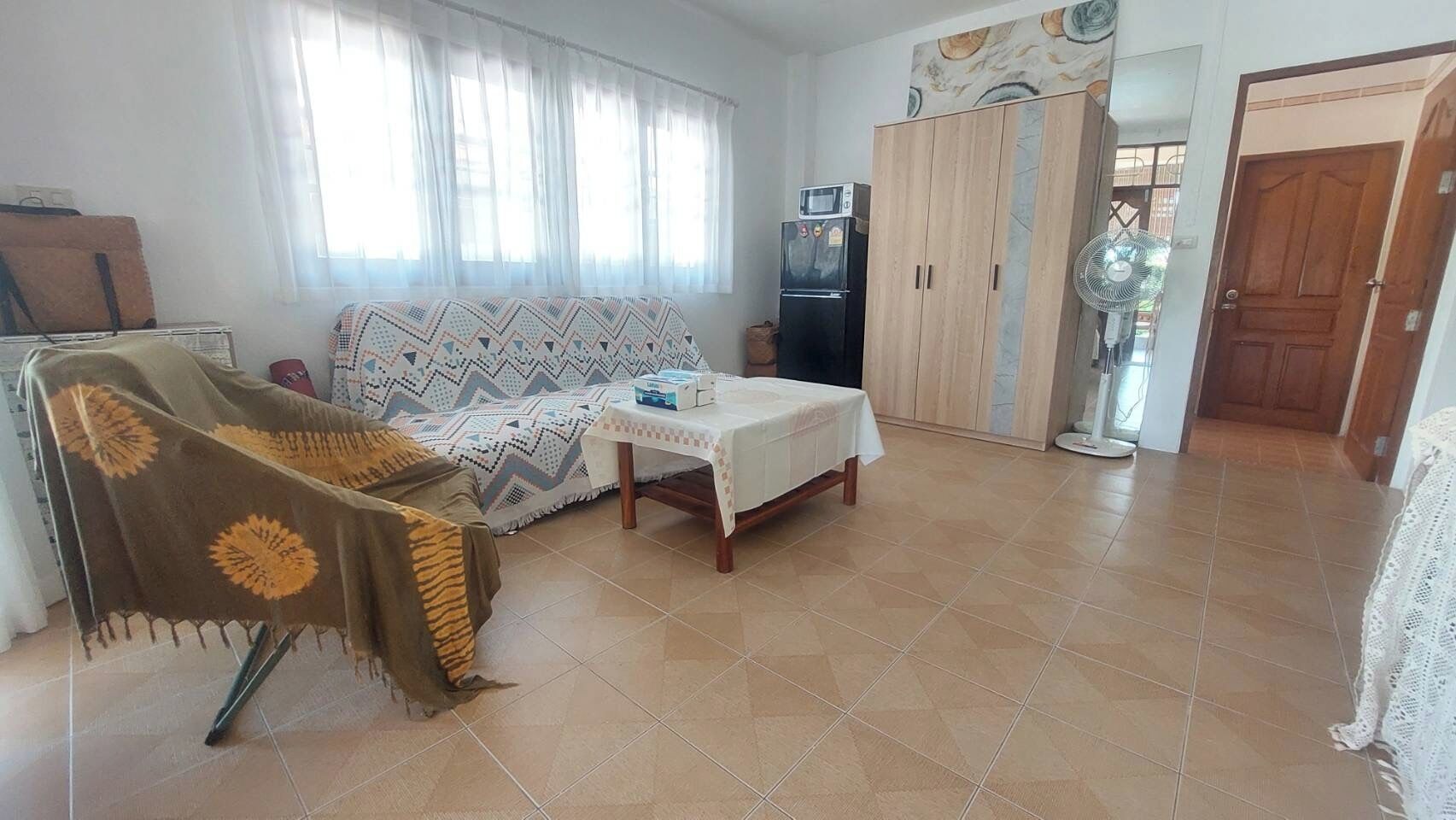 A living room with a sofa, a table, a cabinet, and a fan.