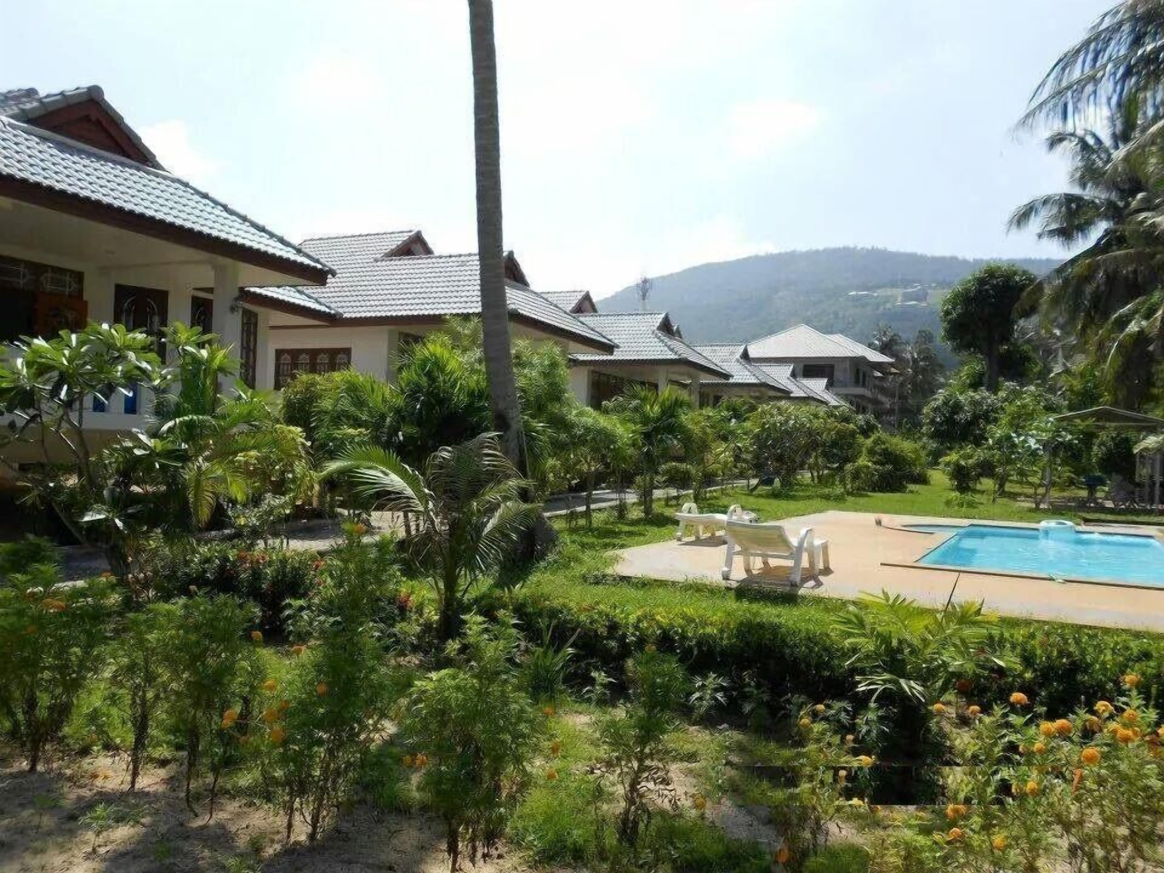 A resort with multiple villas, a swimming pool, and lush greenery.
