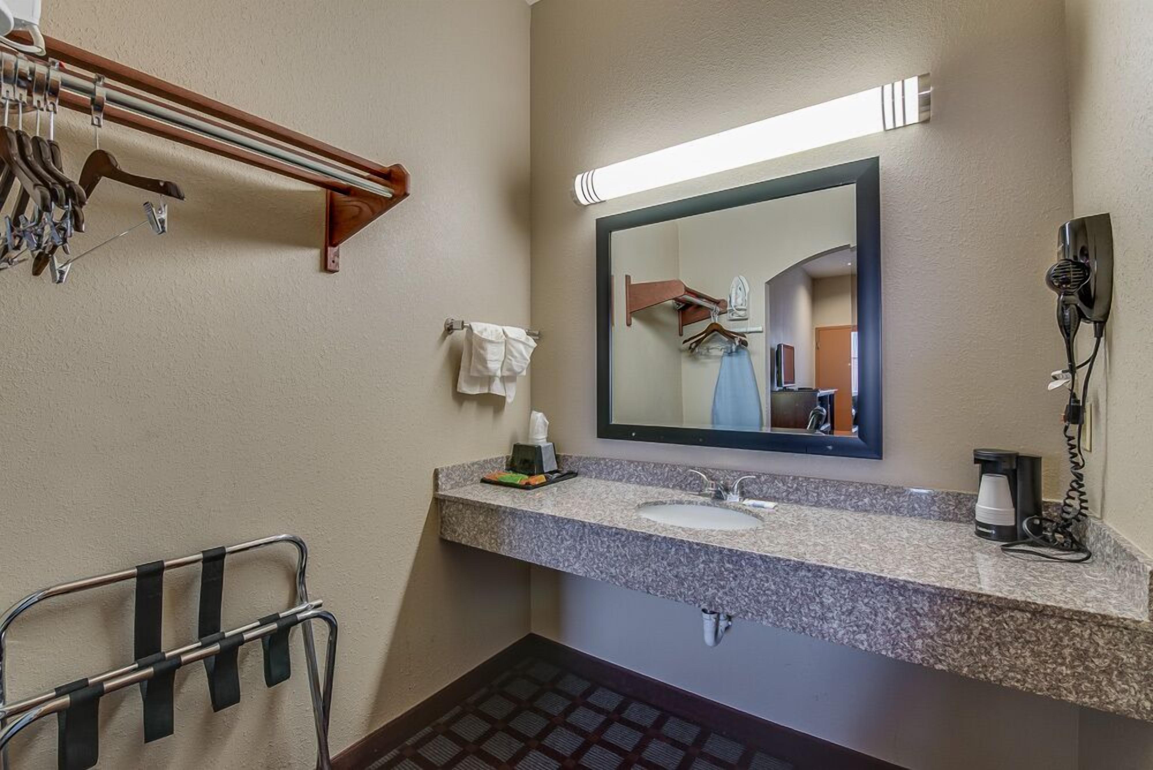 Baño con lavamanos de encimera de granito, espejo, toallero y secador de pelo.