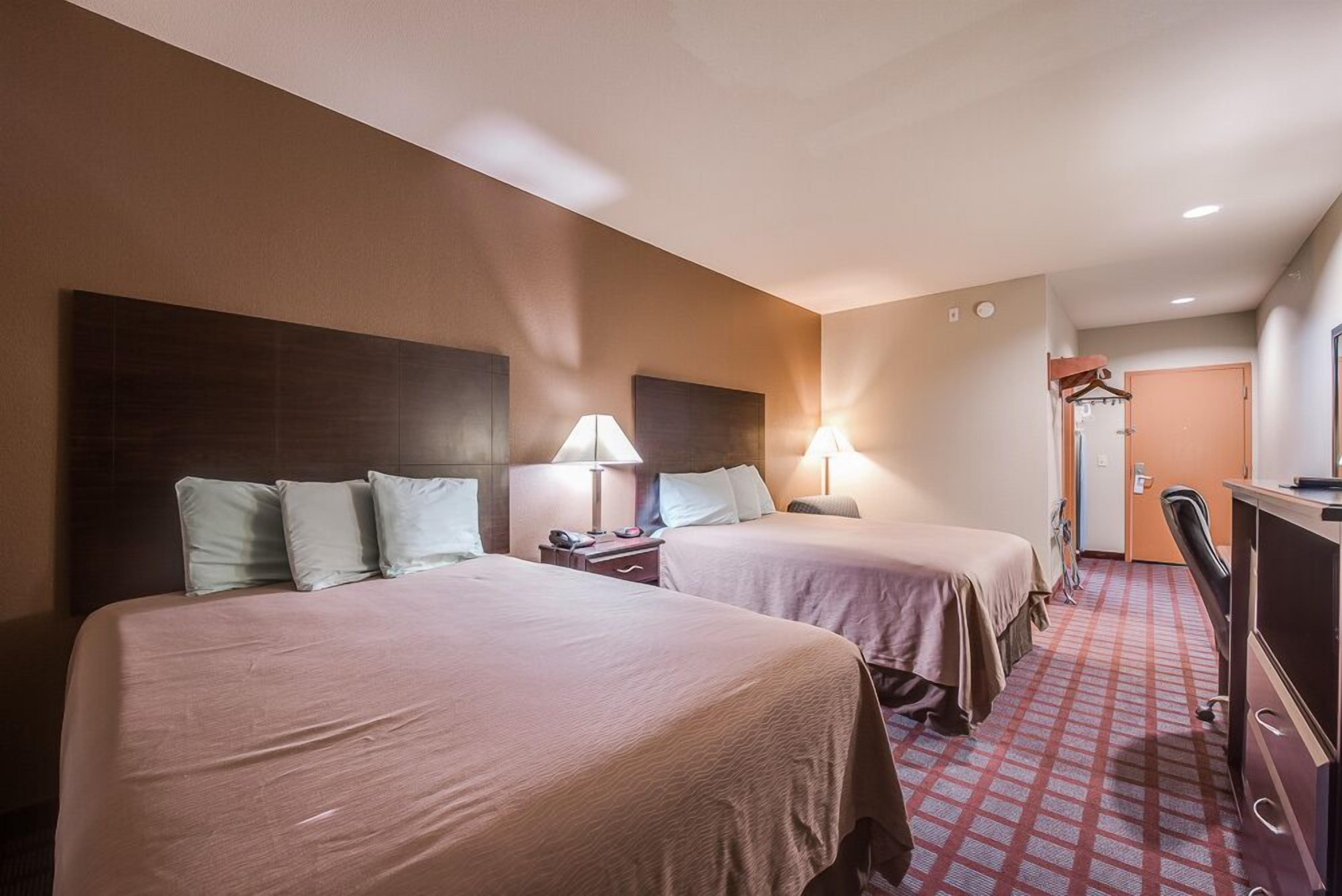 Una habitación de hotel con dos camas, un escritorio, una silla y un armario.