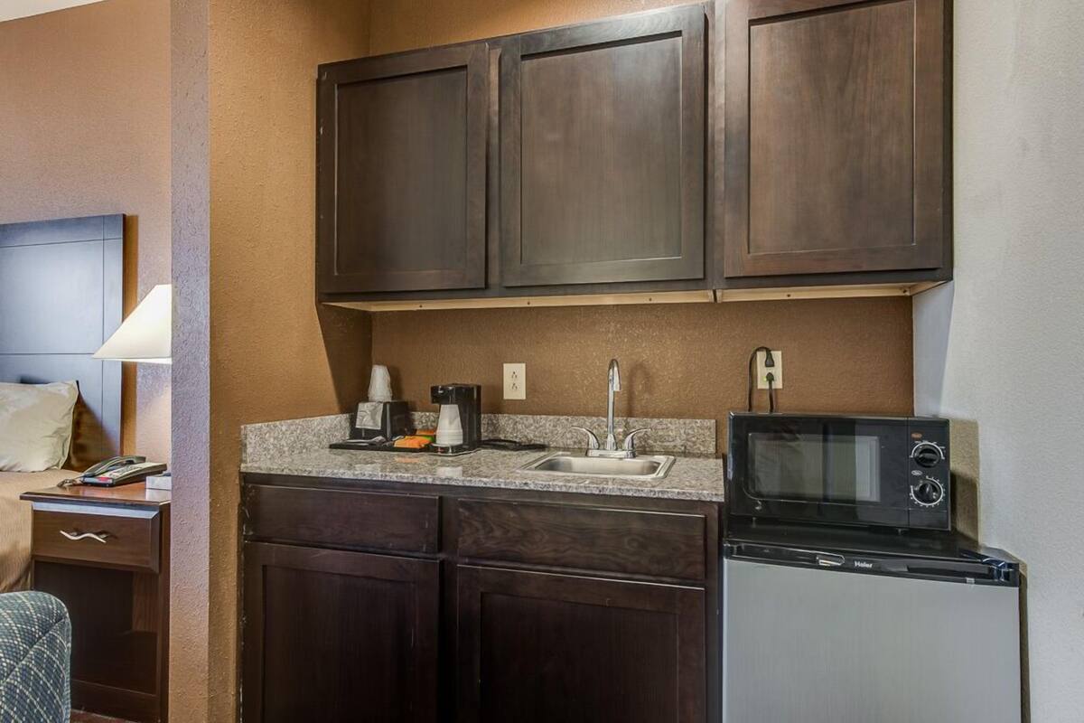 A compact kitchen with dark wood cabinets, a built-in microwave, and a coffee maker.