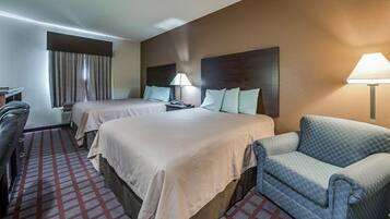 A hotel room with two beds, a desk, a chair, and a sofa.