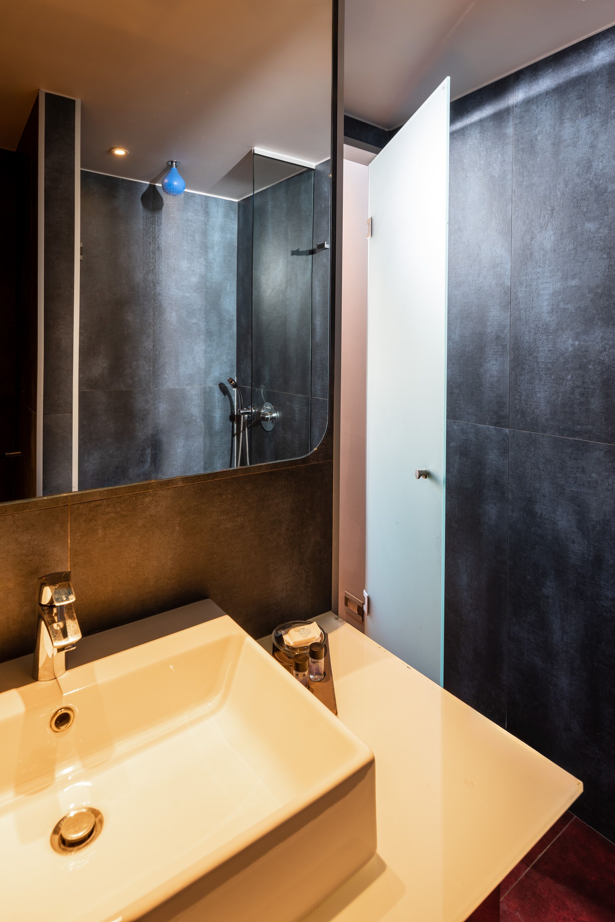 A modern bathroom with a large mirror, a white sink, and a shower area.