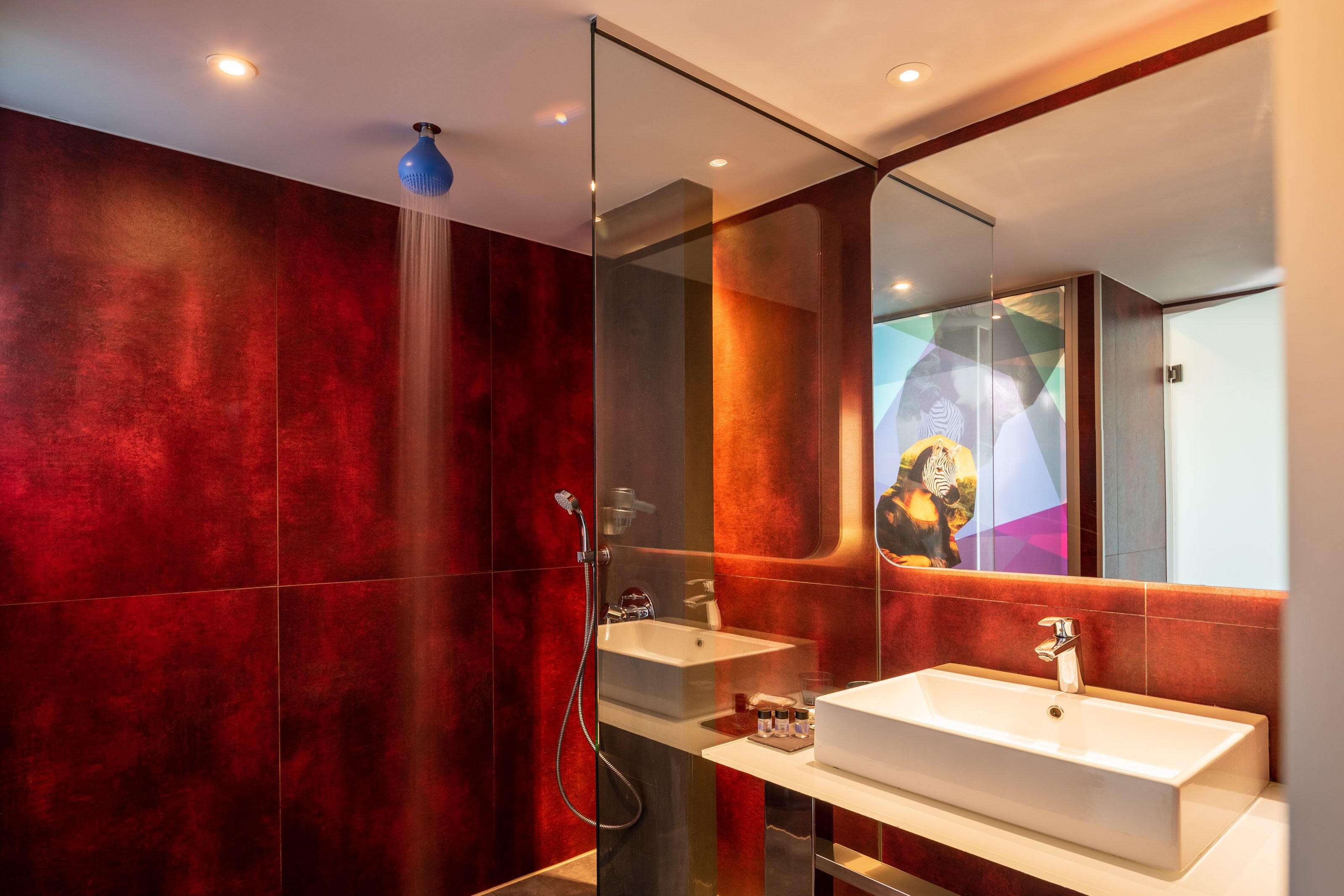 Ein modernes Badezimmer mit Duschkabine aus Glas, einem weißen Waschbecken und einem großen Spiegel.