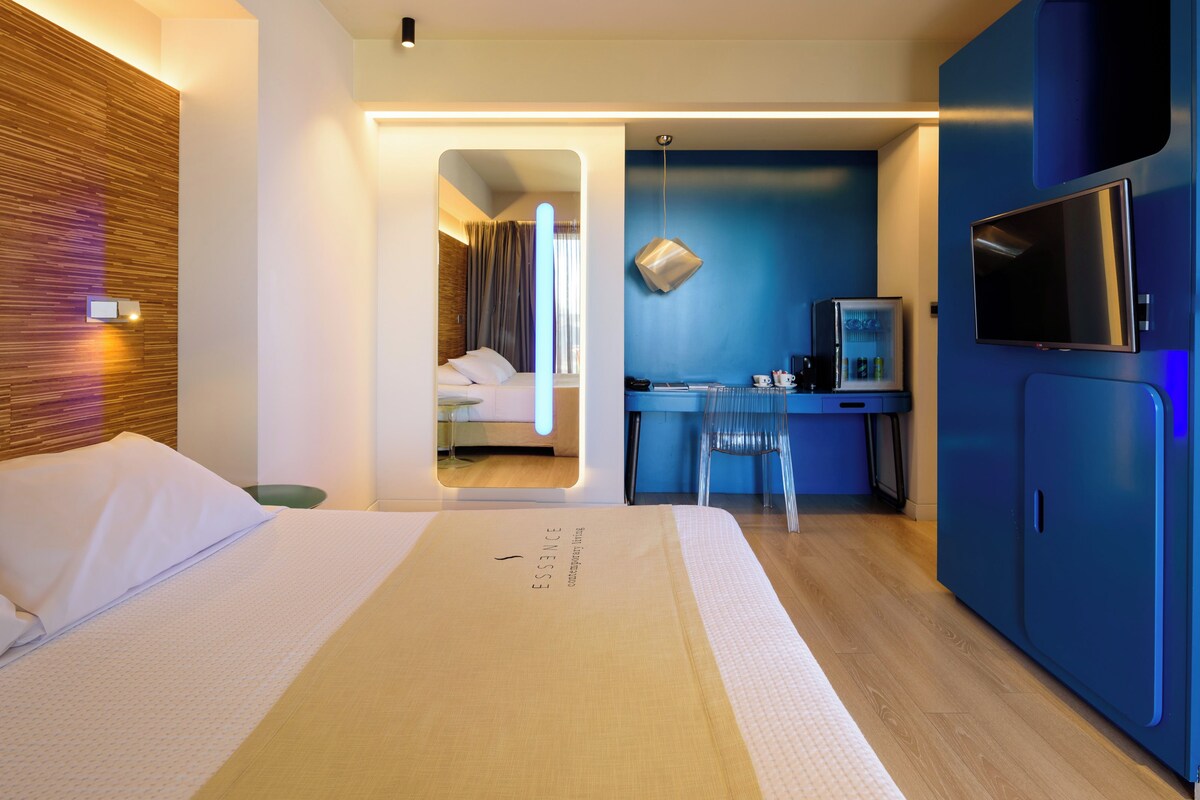 Una habitación de hotel con cama, escritorio, televisor y espejo.