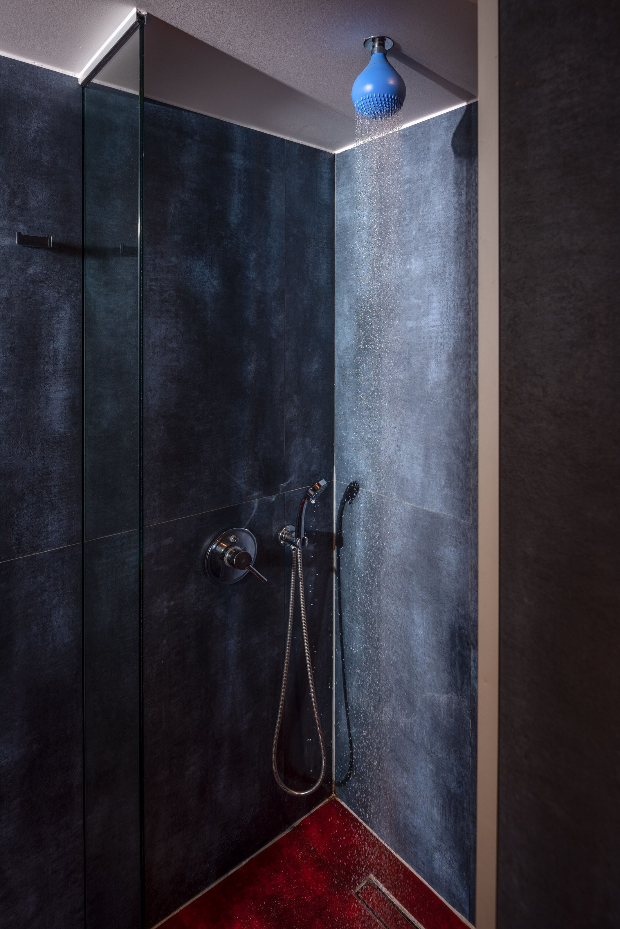Une douche moderne dotée d’un pommeau de douche bleu et d’un flexible.