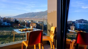 Comedor con una mesa lista para dos personas, con vistas a un paisaje escénico de montañas y valle.