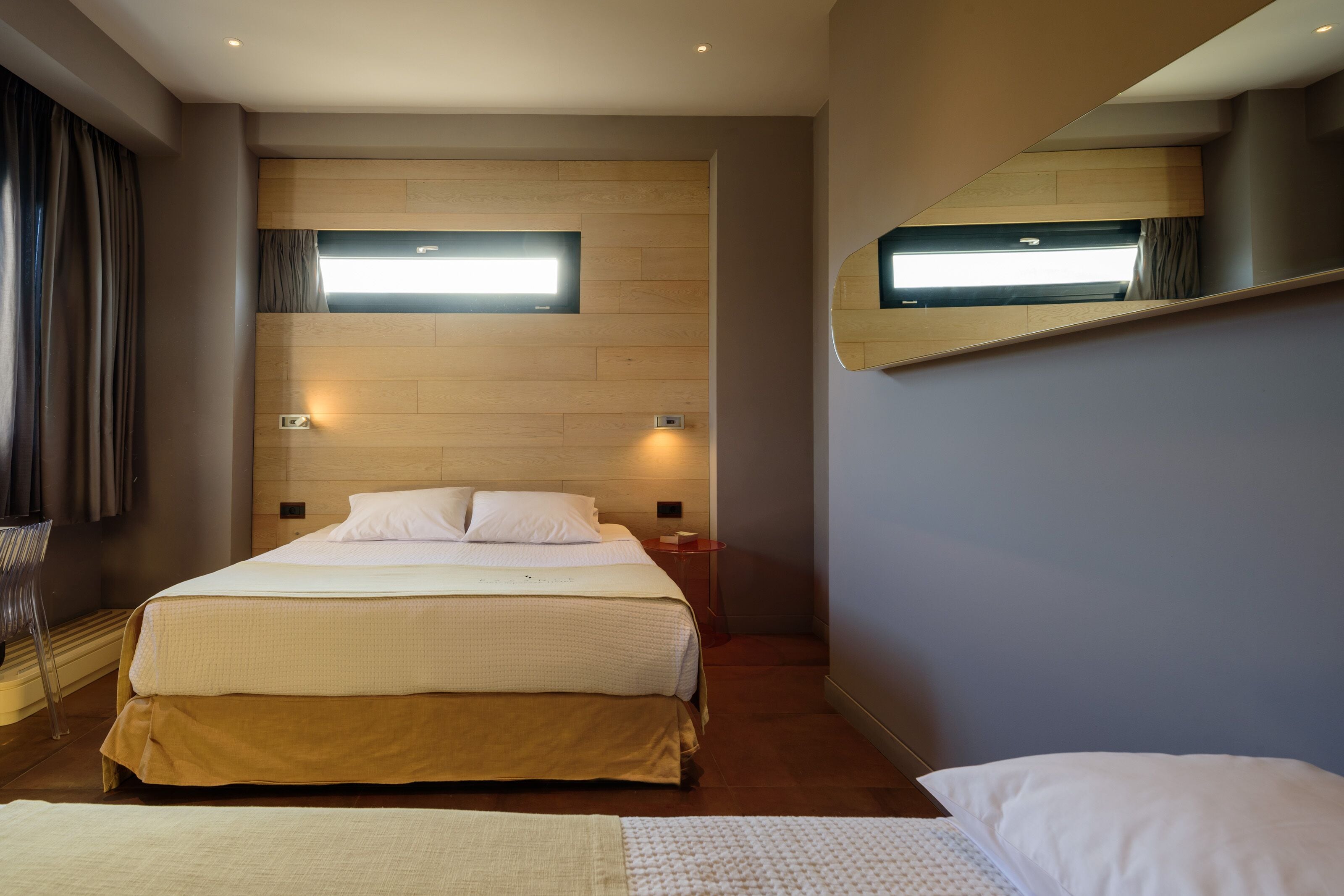 Een moderne hotelkamer met een groot bed, een nachtkastje, een spiegel en een raam met gordijnen.