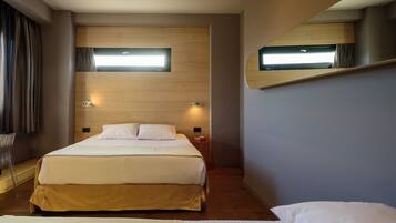 Een moderne hotelkamer met een groot bed, een nachtkastje, een spiegel en een raam met gordijnen.