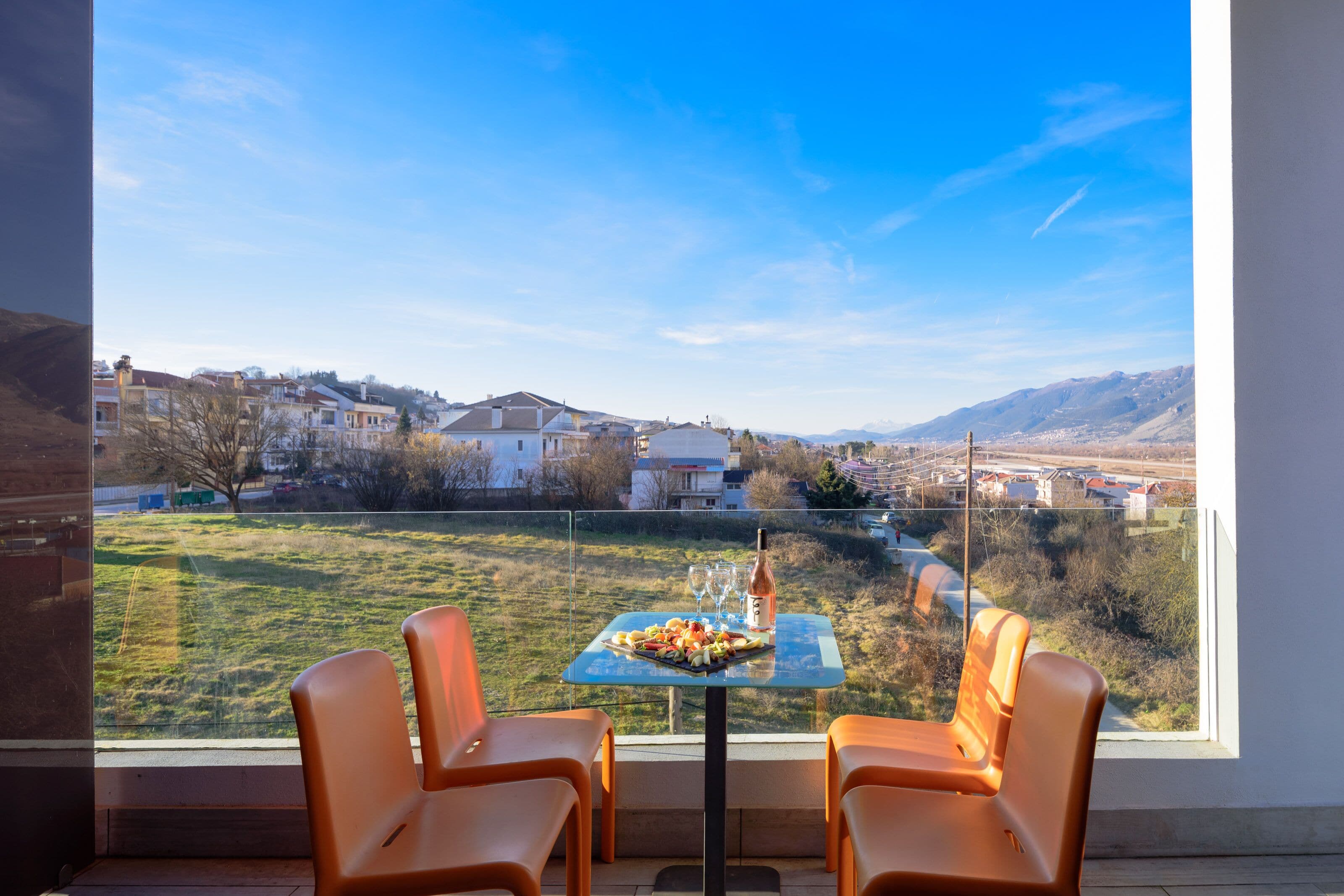 A dining area with a table set for two, overlooking a residential neighborhood and mountains.